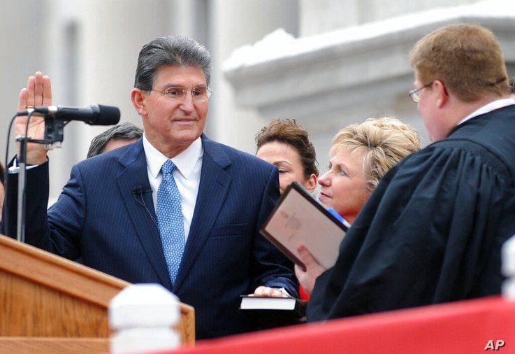 Gov. Joe Manchin, left, is sworn into office for a second term by Supreme Court Justice Brent Benjamin, right, while first lady…