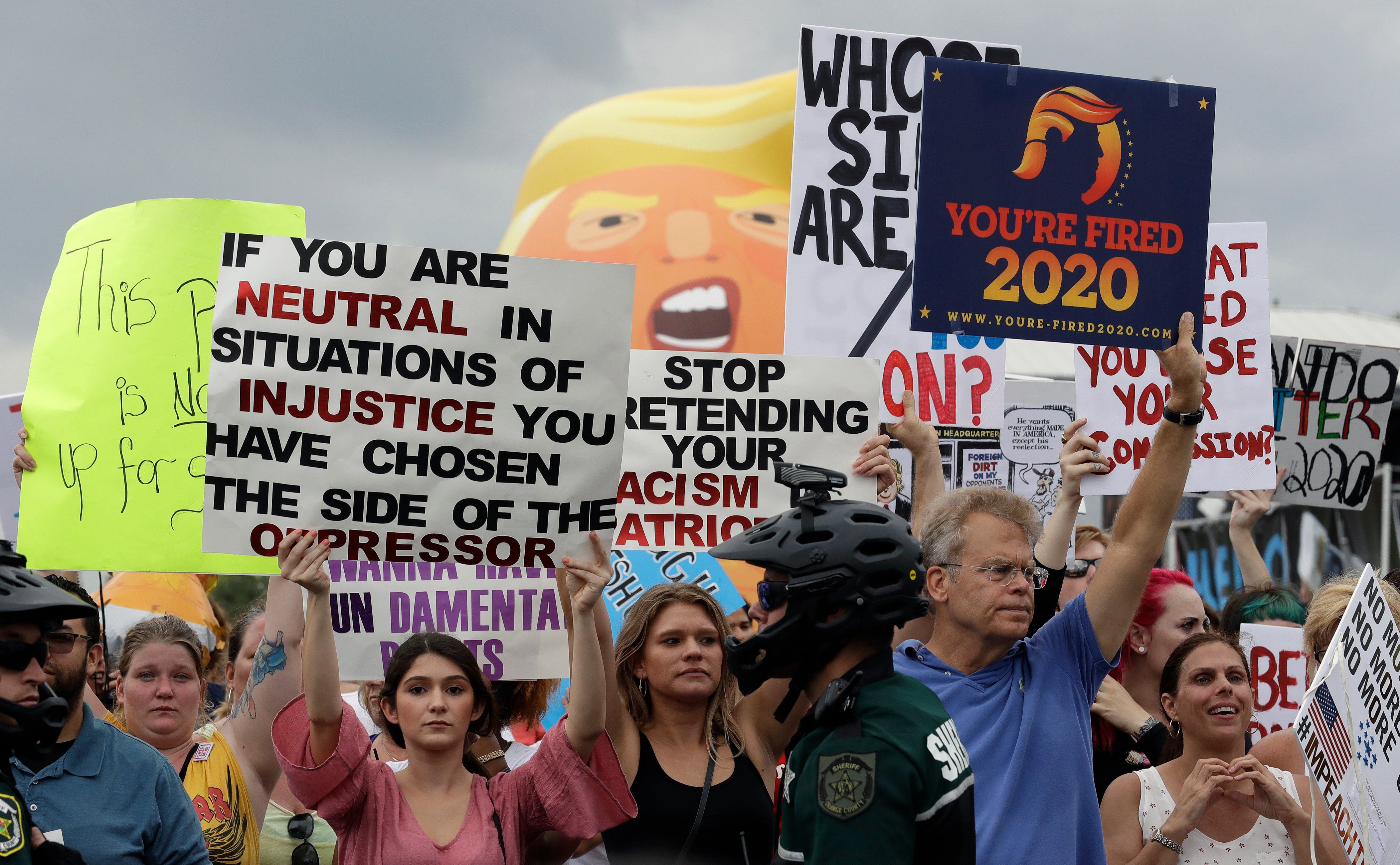 Protestors hold up anti President Donald Trump signs during a rally Tuesday, June 18, 2019, in Orlando, Fla. 