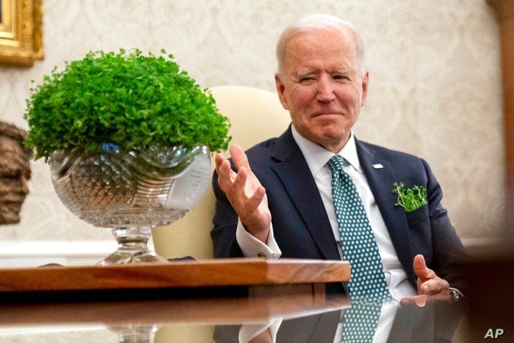 President Joe Biden sits next to a bowl of Irish shamrocks, left, as he has a virtual meeting with Ireland's Prime Minister…