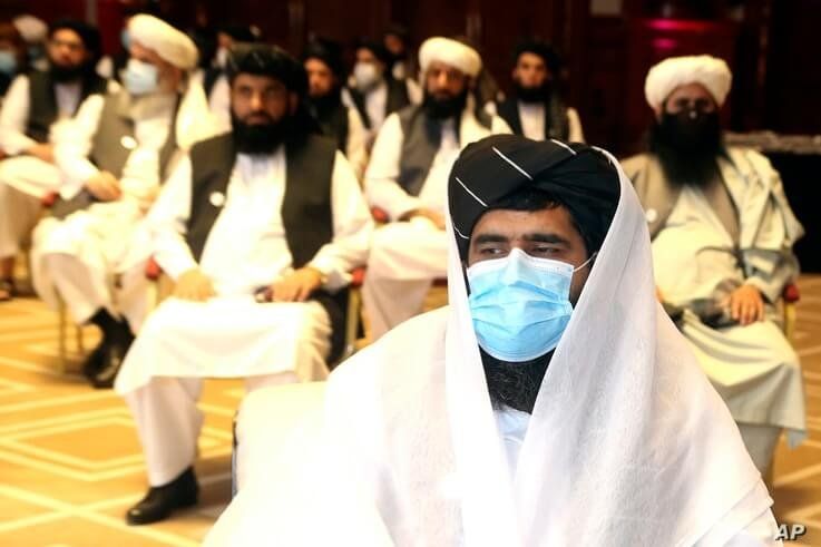 A member of Taliban negotiation delegation, keeps his face mask during the opening session of the peace talks between the…