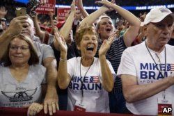 FILE - Supporters of President Donald Trump, wearing Mike Braun for Congress shirts, cheer as he arrives for a campaign rally at the Ford Center in Evansville, Ind., Aug. 30, 2018.