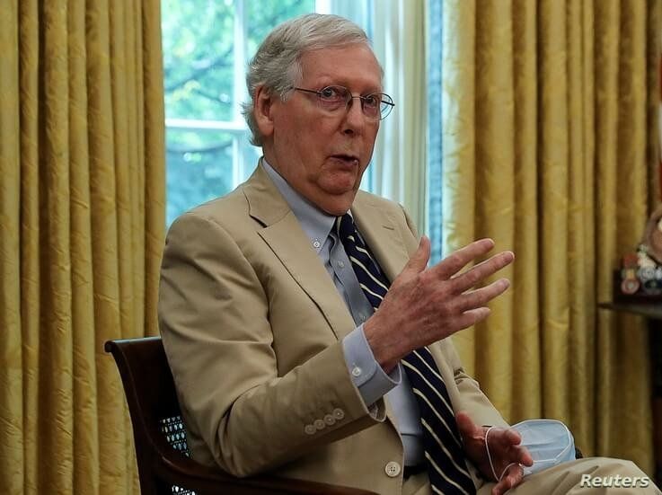 U.S. Senate Majority Leader Mitch McConnell (R-KY) holds onto a protective face mask as he speaks about legislation for…