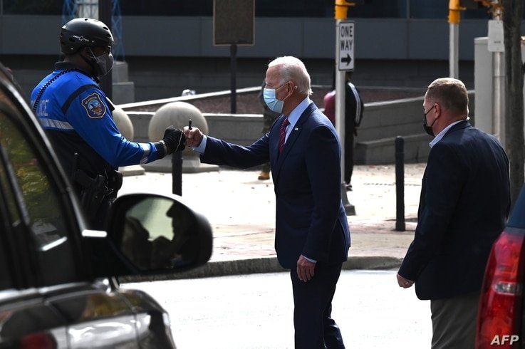FILE - Then-Democratic presidential candidate Joe Biden fist bumps a police officer as he departs The Queen theater after taping an interview, in Wilmington, Delaware, Oct. 19, 2020.