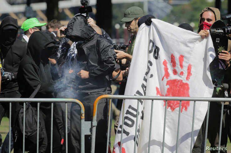 FILE - Antifa counter-protesters, rallying against right-wing group Patriot Prayer, light a smoke grenade in Portland, Oregon, Sept. 10, 2017. 
