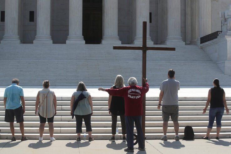 Demonstrators gather outside the U.S. Supreme Court as the court ruled that religious institutions like churches and schools…